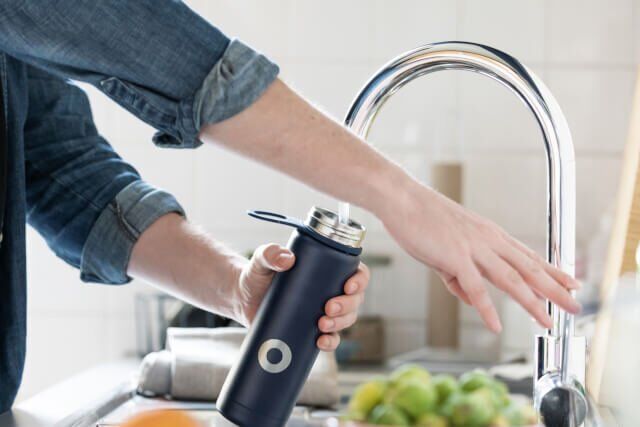 man putting tap water in bottle